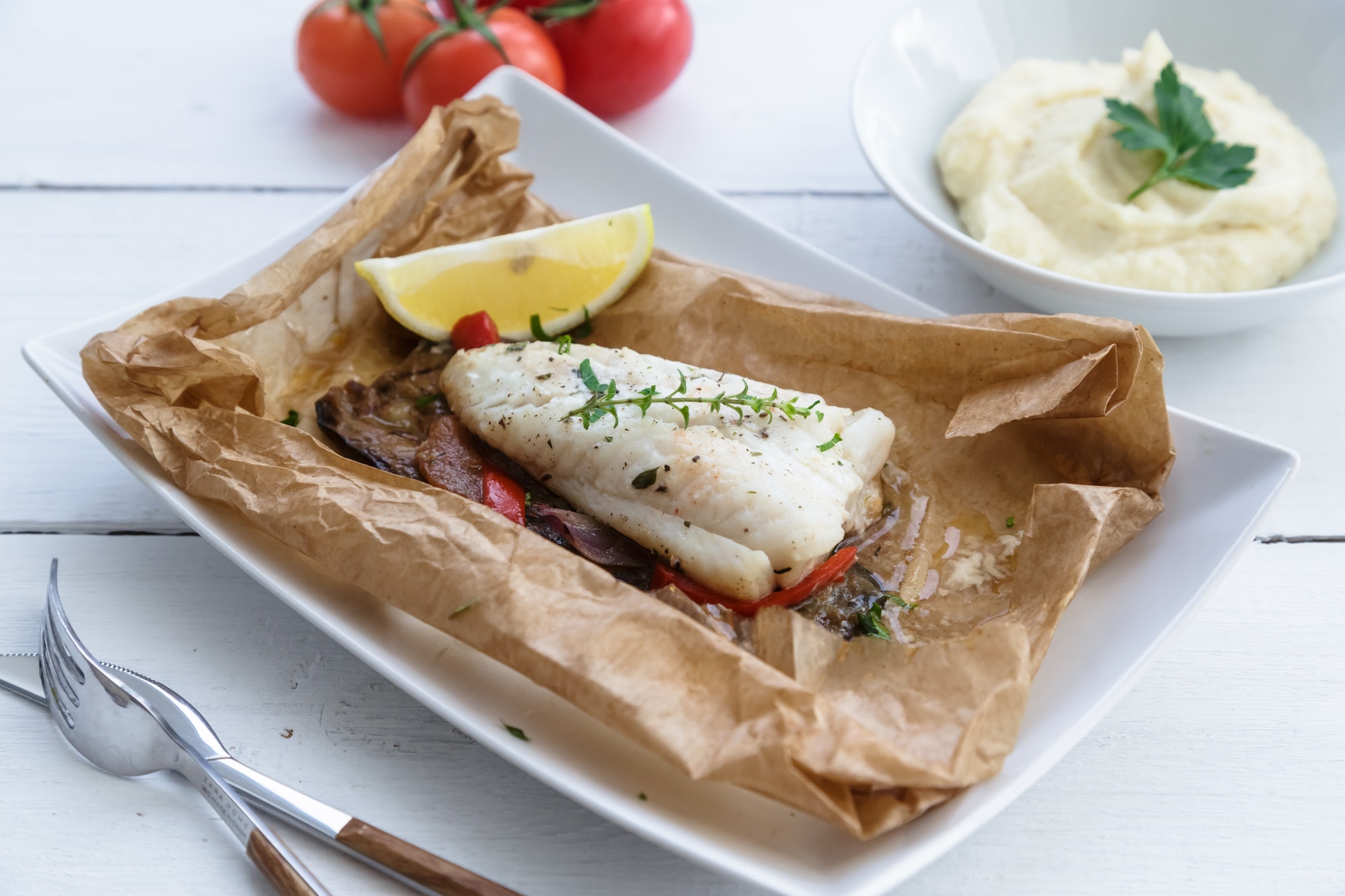 Cod fillets baked in parchment paper with vegetables