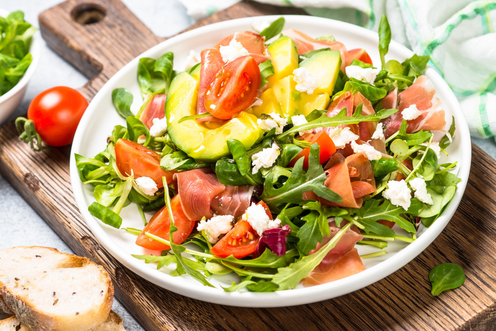 Fresh salad with green leaves, jamon and tomatoes.